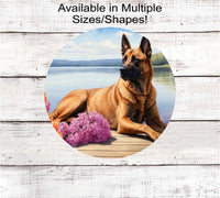 
              A Belgian Malinois dog surrounded by beautiful flowers on a dock overlooking a lake.
            