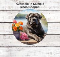 
              A Cane Corso dog surrounded by beautiful flowers on a dock overlooking a lake.
            