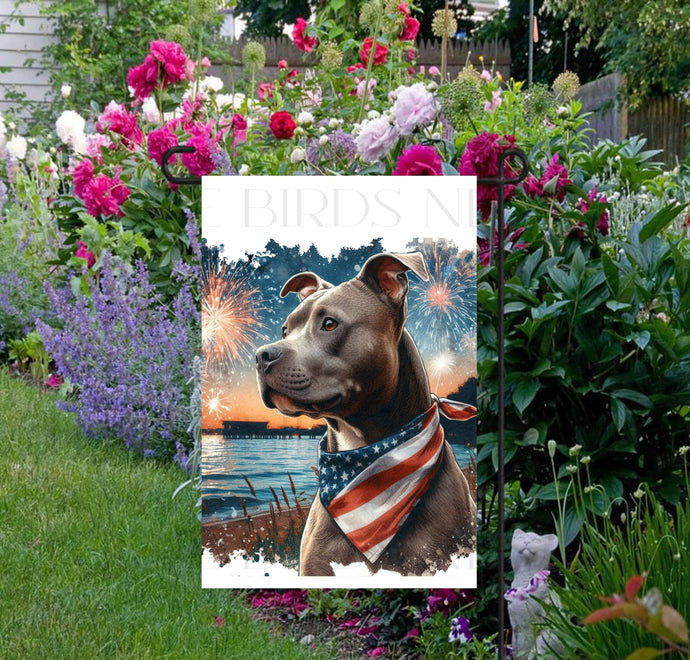 An adorable Pit Bull Dog wearing an American Flag Bandanna on a Beach with Fireworks in the background.