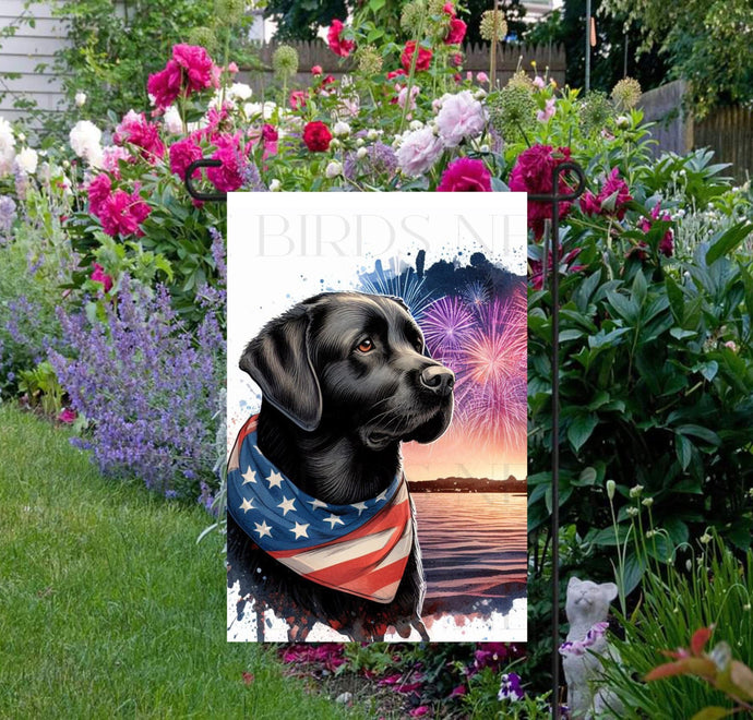 An adorable black Labrador Retriever Dog wearing an American Flag Bandanna on a Beach with Fireworks in the background.