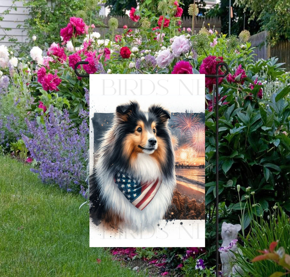 An adorable Shetland Sheepdog wearing an American Flag Bandanna on a Beach with Fireworks in the background.