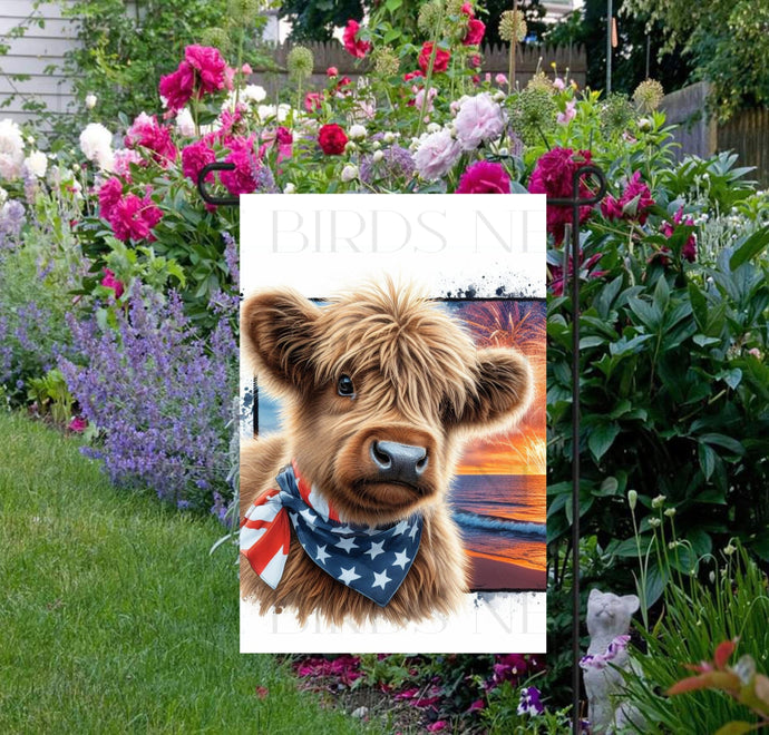 An adorable Scottish Highland Cow Calf wearing an American Flag Bandanna on a Beach with Fireworks in the background.