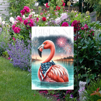 An adorable pink Flamingo wearing an American Flag Bandanna on a Beach with Fireworks in the background.