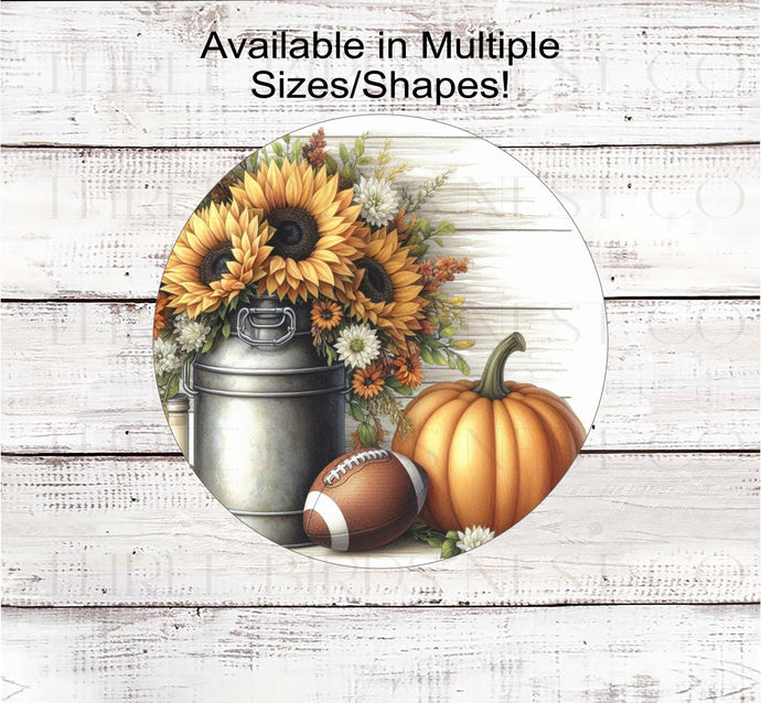 A beautiful rustic metal milk can filled with Sunflowers and other Fall flowers next to a pumpkin and a football.