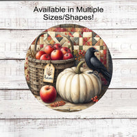 An adorable Primitive Wreath Sign featuring a black Crow sitting on a white pumpkin, next to a basket of fresh apples with pip berries all around. The background is a Fall colored quilt.