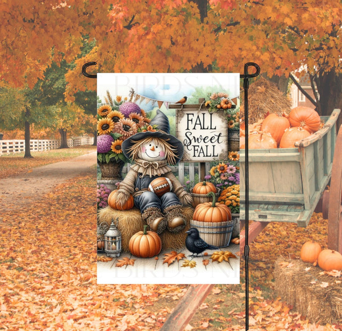 A beautiful Fall Sweet Fall Garden Flag with a cute Scarecrow holding a football and surrounded by pumpkins and mums.