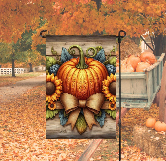 A beautiful rustic Fall Garden Flag with a decorated carved Pumpkin surrounded by sunflowers and a burlap bow.