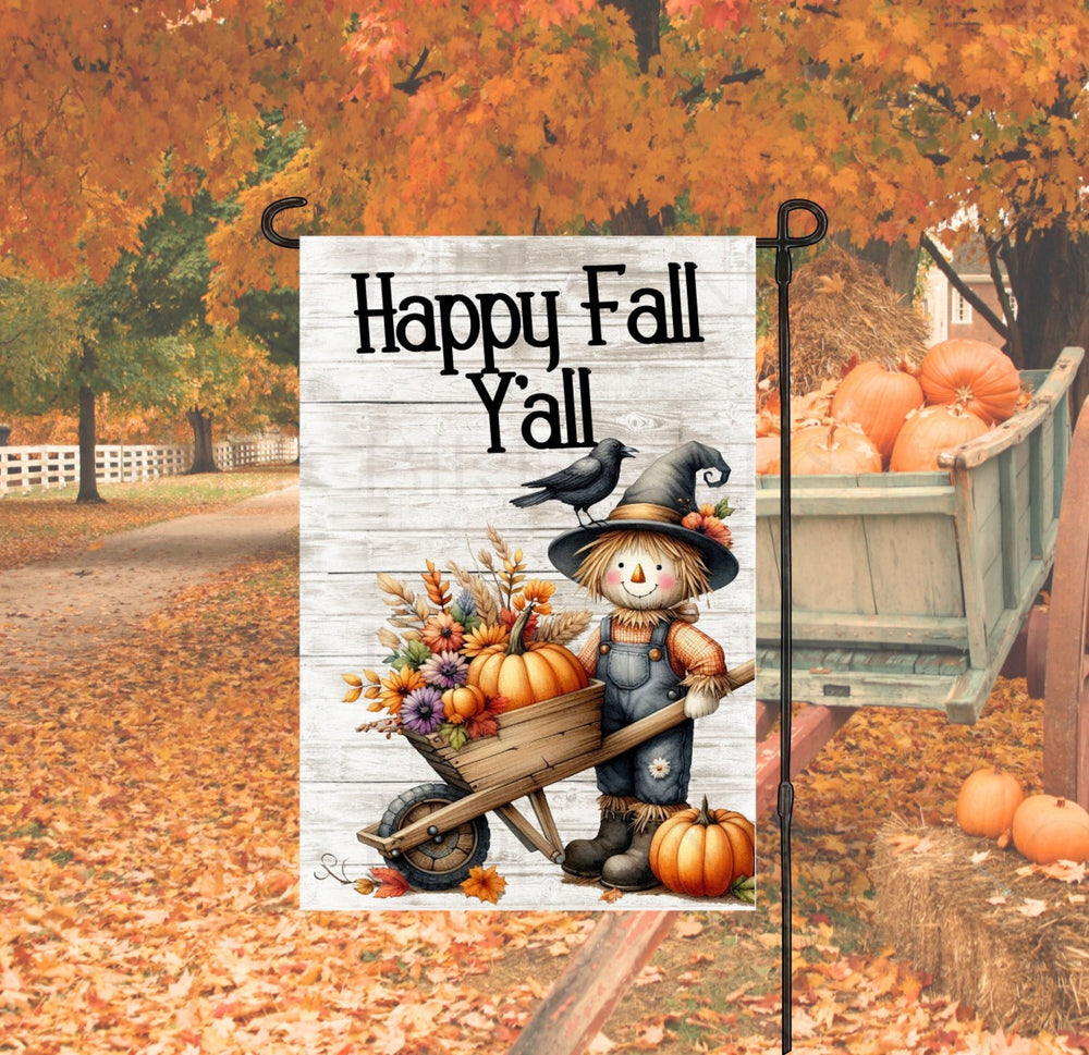 A beautiful Happy Fall Yall Garden Flag with a Scarecrow and his black Crow friend pushing a wheelbarrow filled with pumpkins and Fall flowers and foliage.