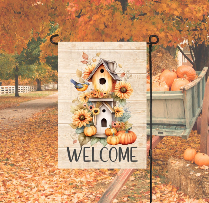 A beautiful Fall Welcome Garden Flag with a birdhouse decorated for Fall with sunflowers and pumpkins.