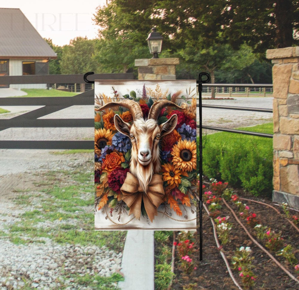 A rustic Farmhouse Garden Flag featuring a Goat surrounded by Sunflowers and beautiful florals with a burlap bow.