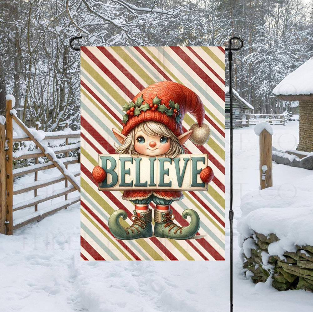 An adorable Christmas Elf with a sign that says BELIEVE- this Garden Flag is perfect for your Winter yard decor.