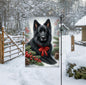 A black German Shepherd in a Winter setting with a red bow on