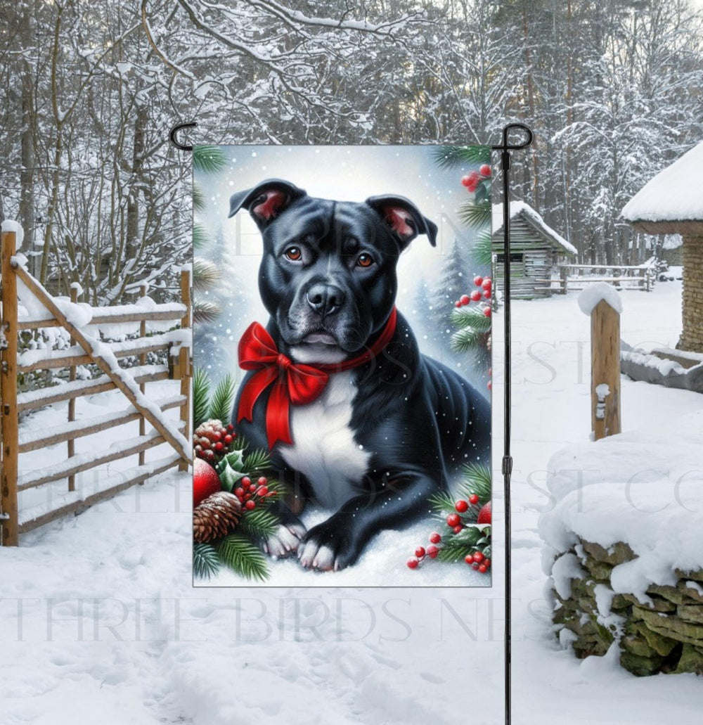 An adorable black and white Pit Bull dog in a snowy Winter setting wearing a red bow.