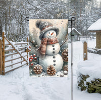 
              An adorable Snowman Garden Flag surrounded by pinecones, branches and berries on a snowy rustic background.
            