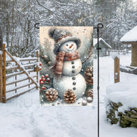 An adorable Snowman Garden Flag surrounded by pinecones, branches and berries on a snowy rustic background.