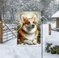 An adorable Corgi dog in a snowy Winter setting wearing a red bow.