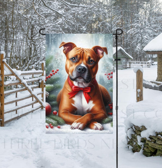 An adorable brown and white Pit Bull dog in a snowy Winter setting wearing a red bow.