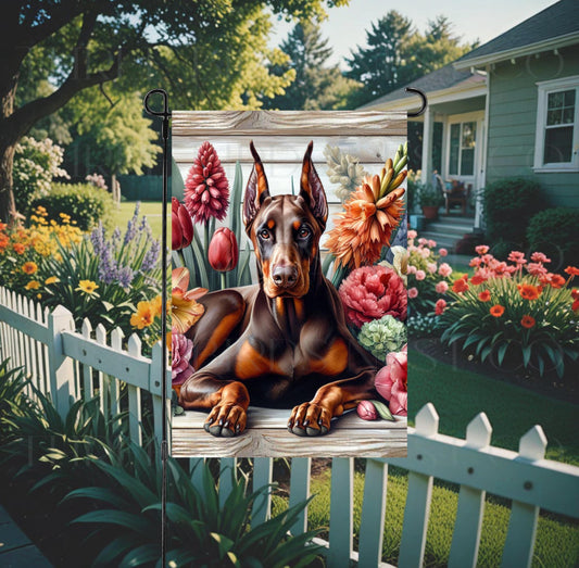 A beautiful red Doberman Pinscher dog surrounded by gorgeous flowers.