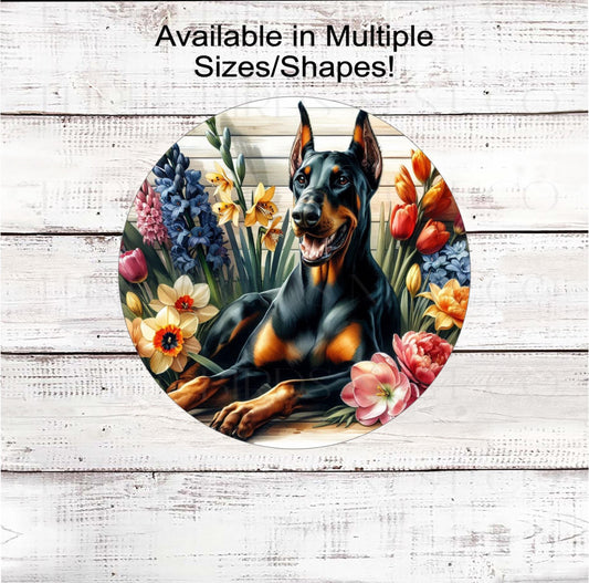 An adorable black and rust Doberman Pinscher surrounded by beautiful Spring Flowers.