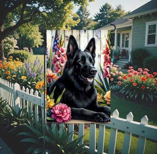 A beautiful black German Shepherd dog surrounded by gorgeous flowers.