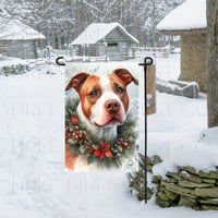 A Red Nosed Pit Bull Dog in a Winter Wonderland setting, wearing a festive collar of greenery and berries with pinecones.