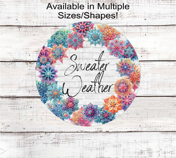 A wooden look sign that says Sweater Weather surrounded by a frame of multi-colored pastel crocheted Snowflakes.