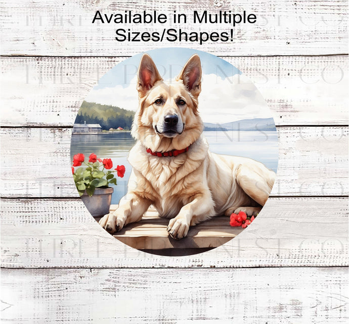 A white German Shepherd dog on a dock with a flower pot overlooking a lake.