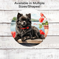 A black Pomeranian Dog on a dock with a flower pot overlooking a lake.