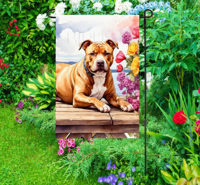 A beautiful tan and white Pit Bull on a dock overlooking a Lake.